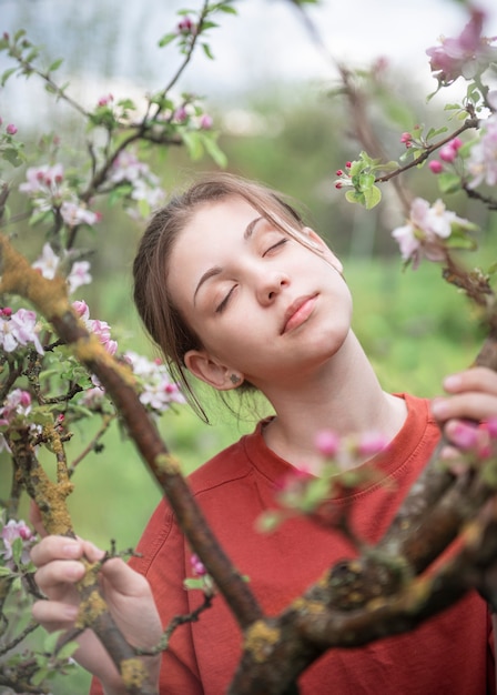 A young girl in a blooming garden looks at flowering trees