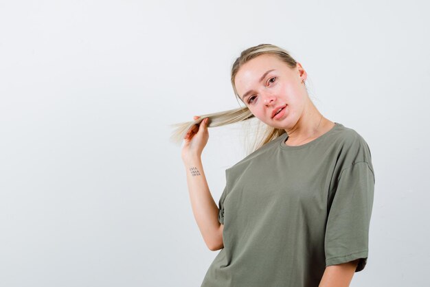 Young girl bowing her head to the right and holding her hair with her left hand on white background