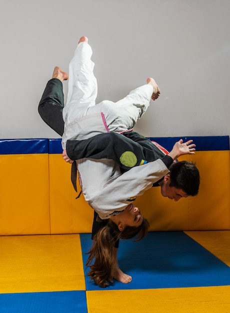 Young girl and boy practice Brazilian jiu jitsu in the gym