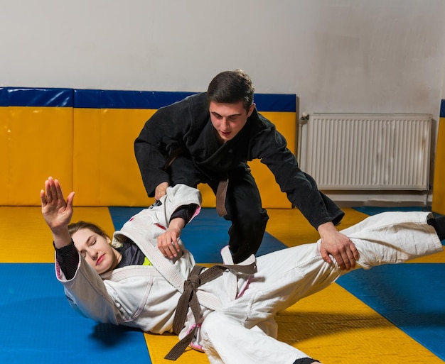 Young girl and boy practice Brazilian jiu jitsu in the gym