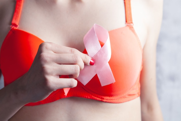 Young girl in bra holding a pink ribbon