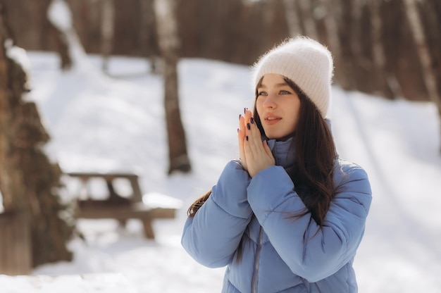 Young girl breathes on her hands to keep warm at cold winter day