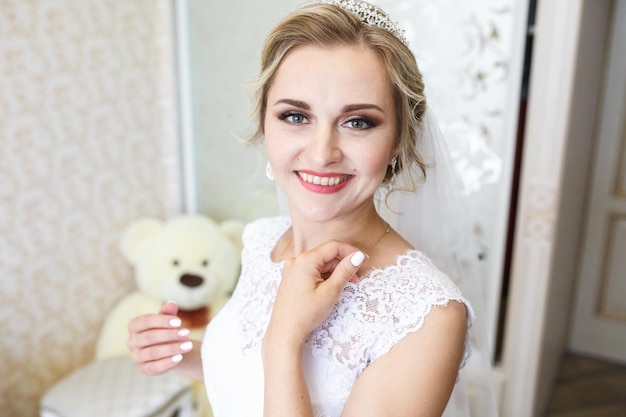 Young girl bride in wedding dress is waiting for the groom with big white bear