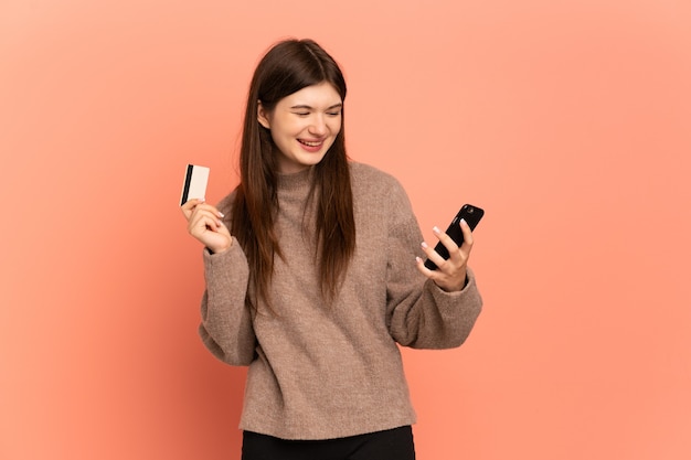 Молодая девушка покупает с мобильного с помощью кредитной карты