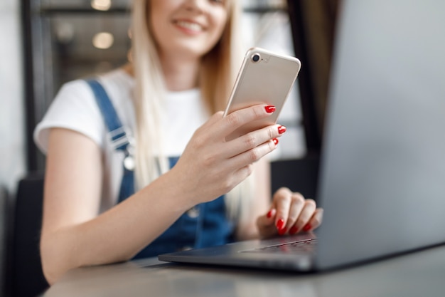 コーヒーを飲みながら携帯電話を使用してカフェで若い女の子。オンラインショッピング