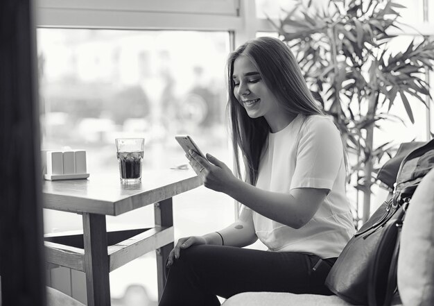 Young girl in a cafe. The girl is sitting on the couch and talking on the phone.