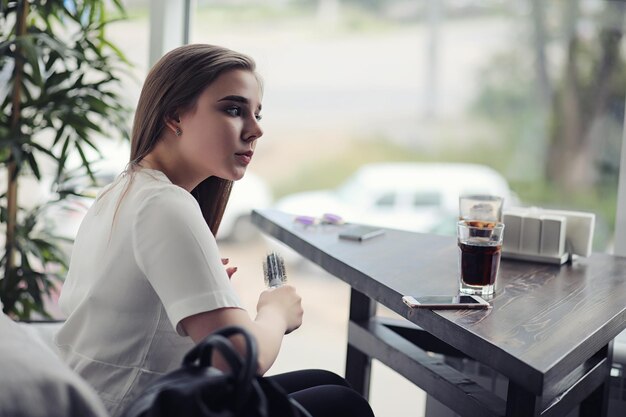 Young girl in a cafe. The girl is sitting on the couch and talking on the phone.