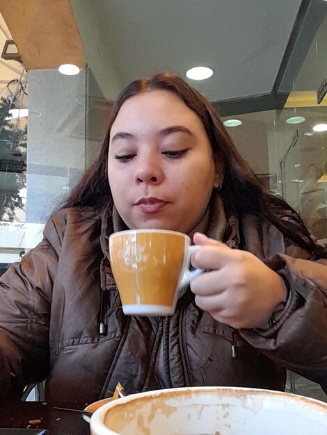 Young girl in cafeteria drinking coffee