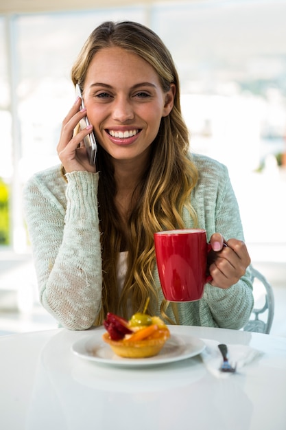 young girl calling while drinking and eating