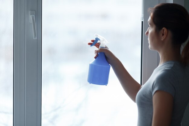 Photo the young girl carefully washes and cleans a window.