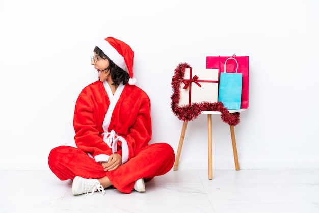 Young girl celebrating Christmas sitting on the floor isolated on white bakcground laughing in lateral position