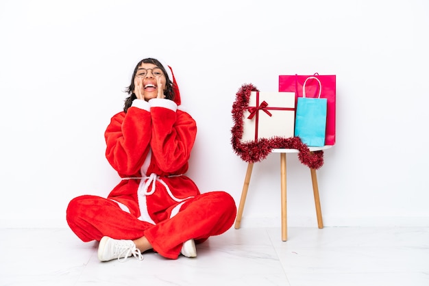 Young girl celebrating Christmas sitting on the floor isolated on white bakcground shouting and announcing something