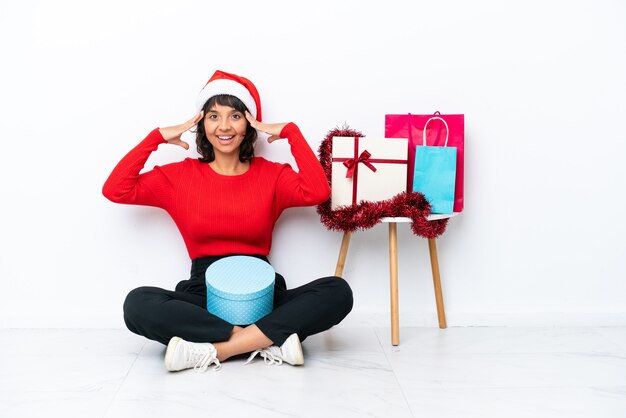 Young girl celebrating Christmas sitting on the floor isolated on white bakcground with surprise expression