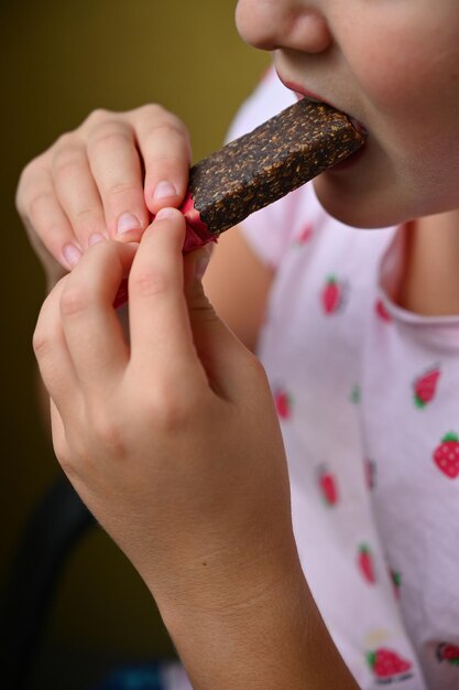 Foto bambina che mangia caramelle e dolci dettaglio del viso e della bocca concetto per uno stile di vita sano cibi dolci e zuccheri non salutari