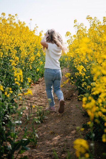 Маленькая девочка бежит по летнему желтому полю сзади фото