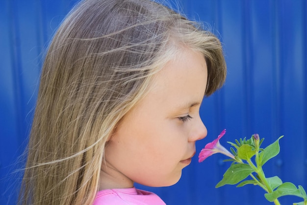 A young girl child sniffs a flower in the fresh air