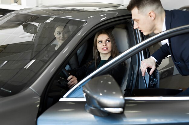 Young girl chooses a car in the salon