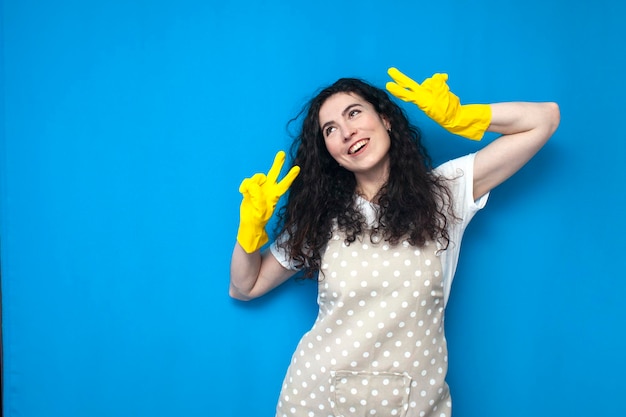 young girl cleaner in uniform and gloves for cleaning shows a gesture of peace