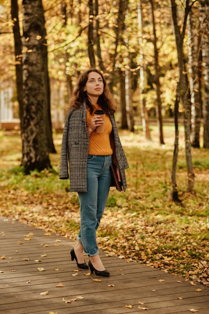 A young girl in a coat walks through the autumn Park