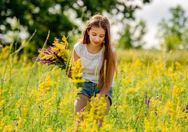 Young girl collecting flowers on field