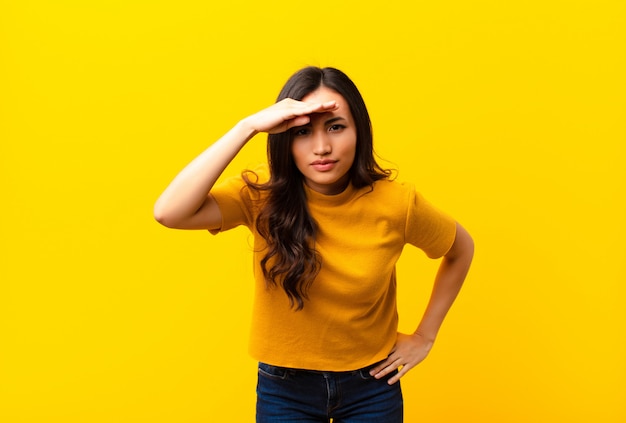 young girl in colorful T-shirt with hand over forehead looking far away