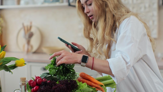 Young girl cooking healthy food salad using mobile cookbook apps in home kitchen Healthcare concept Organic fresh fruit