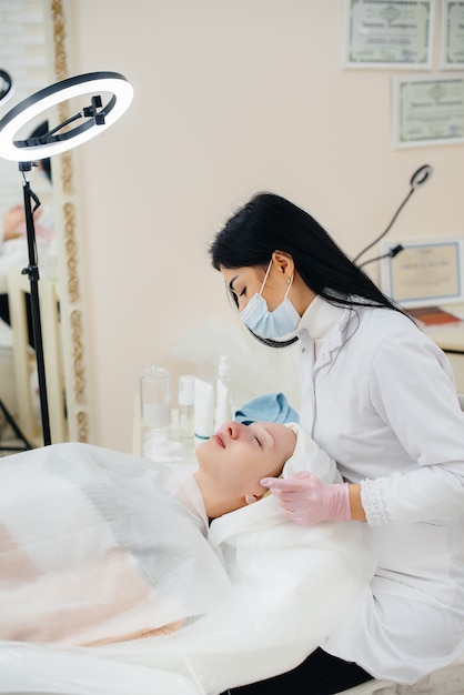 A young girl in a cosmetology office is undergoing facial skin rejuvenation procedures. Cosmetology.