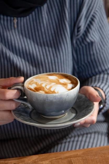 Photo a young girl cradles a warm cup of coffee in her hands