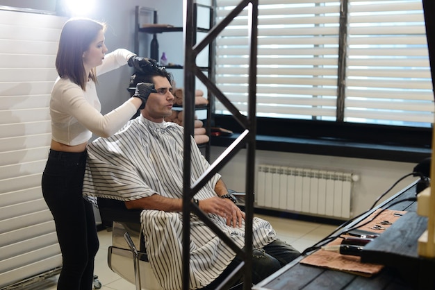 A young girl cuts man in the Barber shop