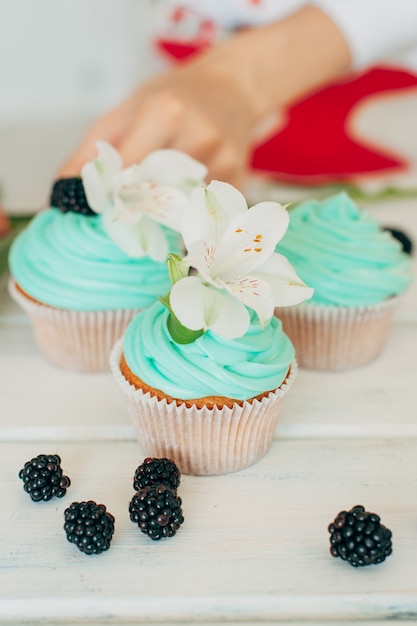 A young girl decorates cupcakes with fresh berries and flowers