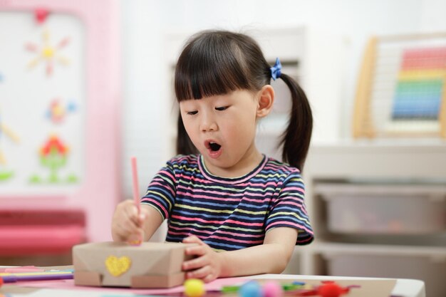 写真 家庭教育のための手作りの工芸品を装飾する若い女の子