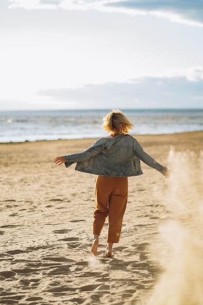 young girl in denim jacket  enjoy sun on beach on summer evening