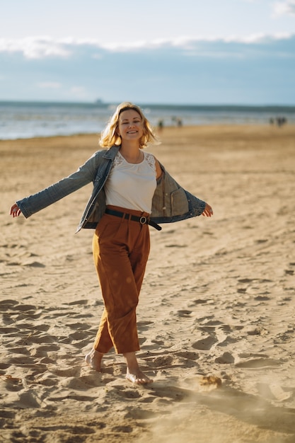 young girl in denim jacket  enjoy sun on beach on summer evening