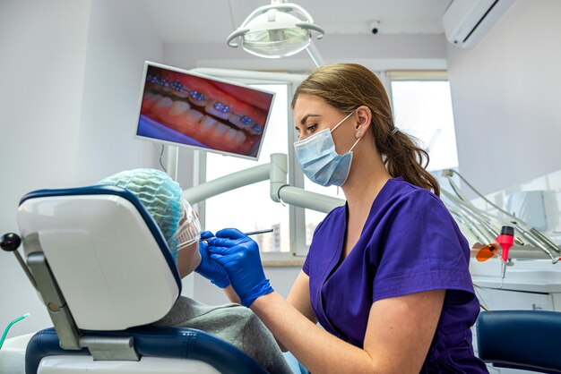 若い女の子の歯科医は彼女の常連客のすべての病気の歯の治療を開始します