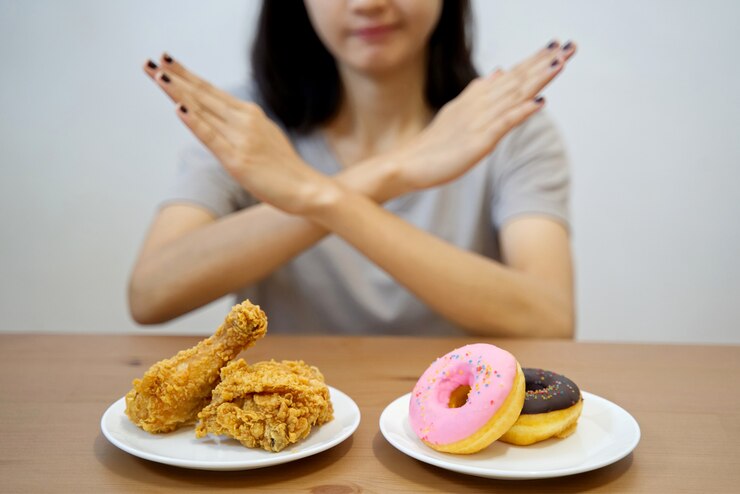 それらの上に彼女の手を渡ることによってジャンクフードを拒否するダイエットの少女