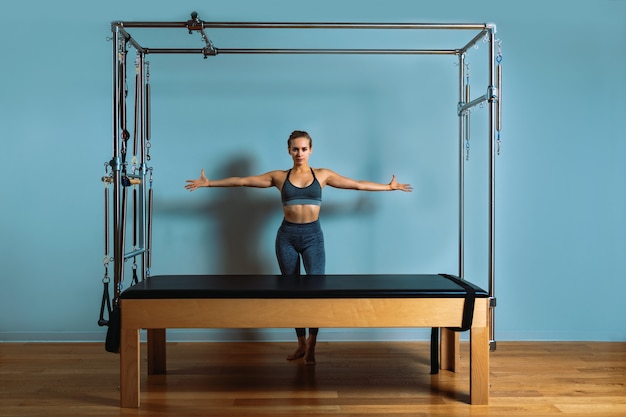 A young girl does Pilates exercises with a bed reformer