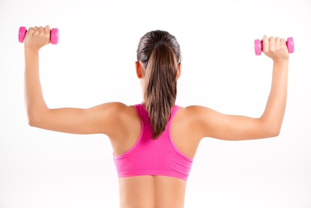 Photo young girl doing exercise to strengthen shoulder with dumbbell. rear view. white background.