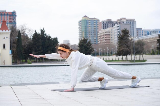 Young girl doing exercises at the park on the yoga mat High quality photo