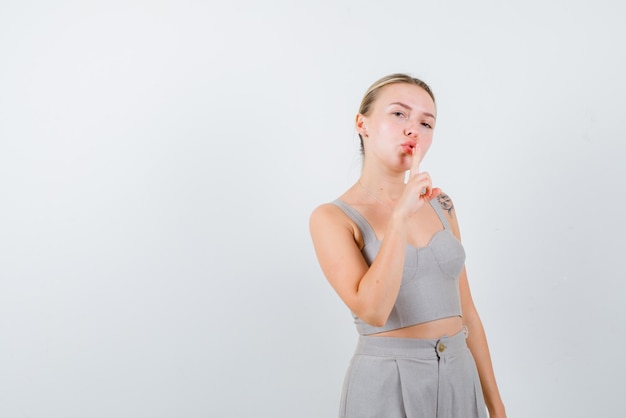 Young girl doing a silence hand gesture on white background