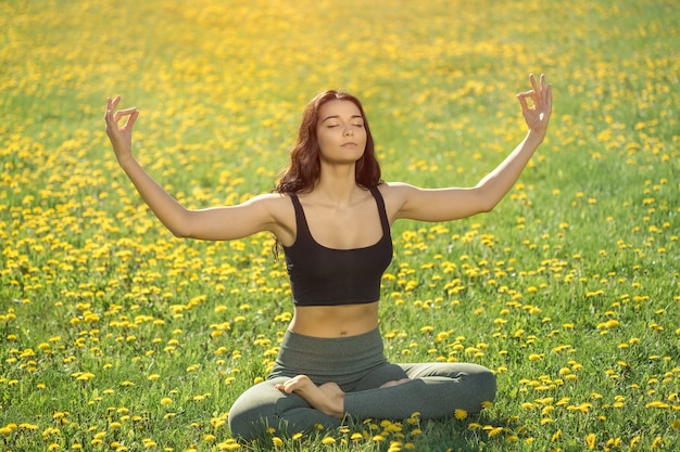 Ragazza che fa yoga nel parco. la donna a praticare yoga eseguendo la posizione del loto all'aperto con