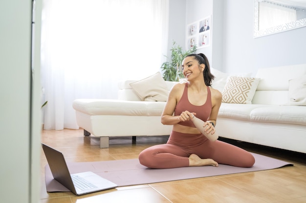 Young girl doing yoga and pilates in the living room of her\
home with the computer