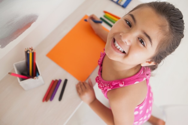 Photo young girl drawing on orange paper