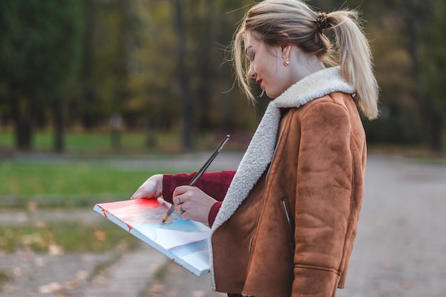 Young girl draws a picture right in the park