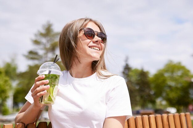 Young girl drinking cool matcha cocktail in sunny weather