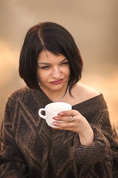 Young girl drinks coffee outdoors emotions