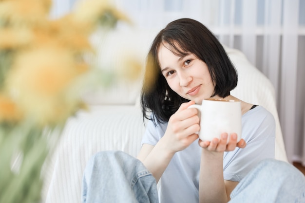 A young girl drinks tea in the living room