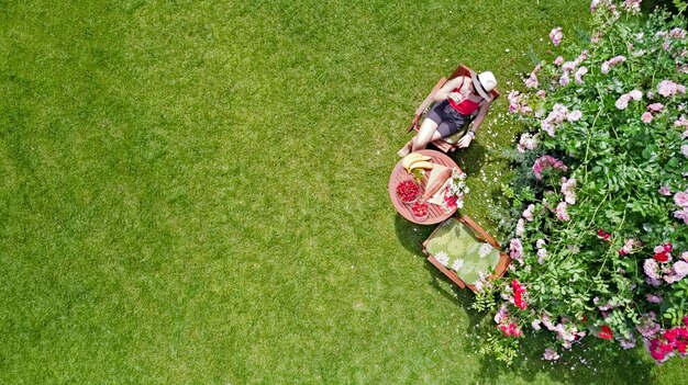 Giovane ragazza che mangia all'aperto in giardino estivo donna ha picnic e relax nella vista aerea del parco