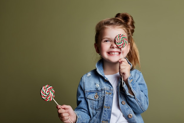 Young girl eating round candy licks Lollipop