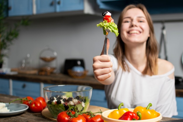 Young girl eating salad at home in the kitchen