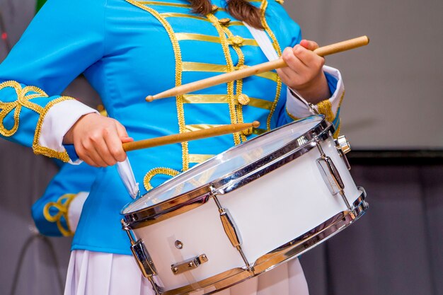 Young girl in elegant suit plays on drum